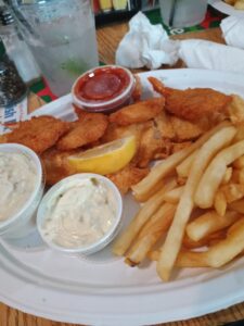 A platter of fried fish and shrimp with fries, lemon and dipping sauces