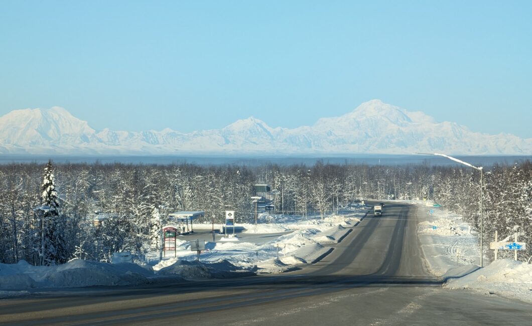 Looking down the snow-covered road through Willow, Alaska, with Denali rising in the distance